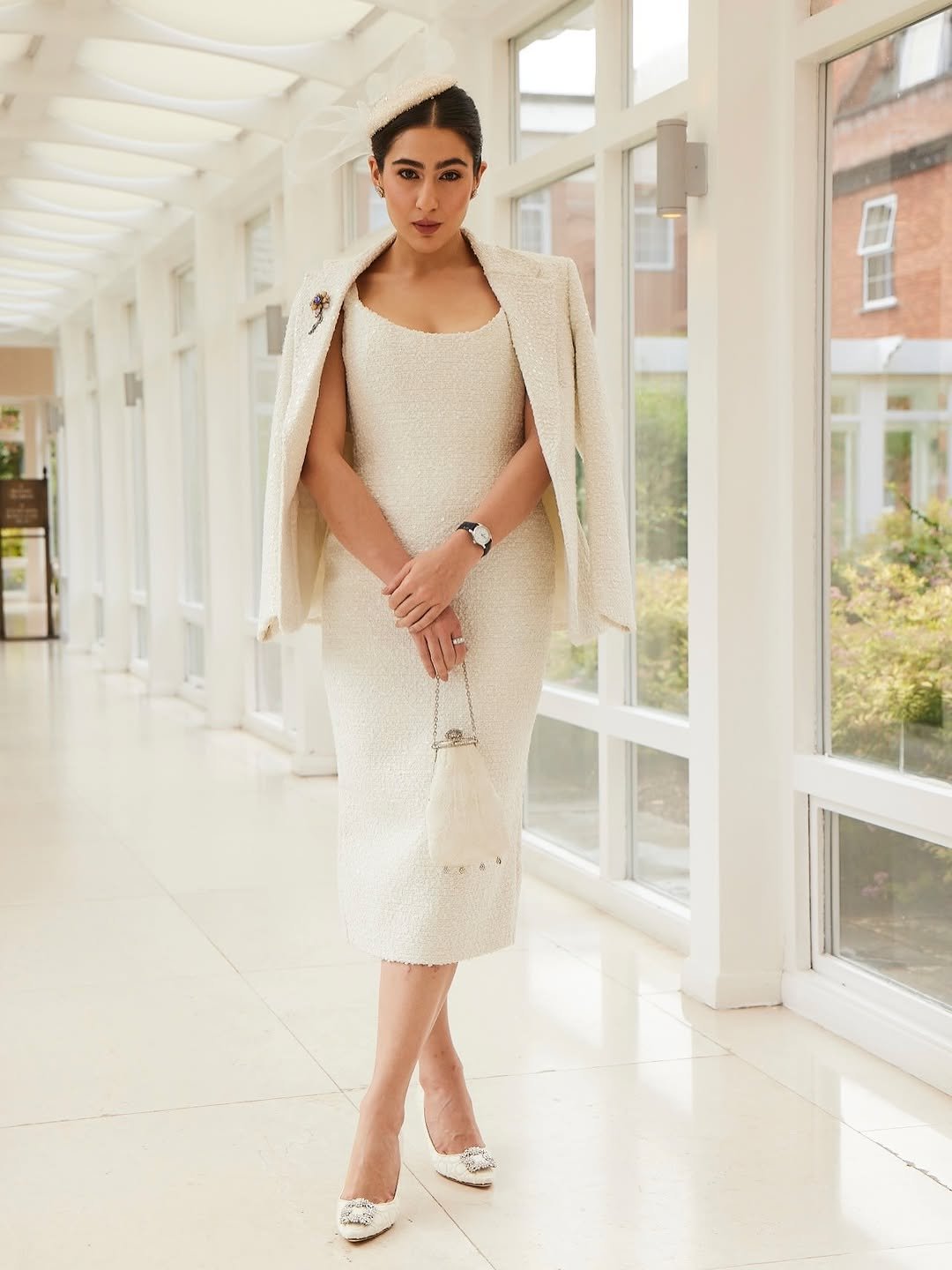 Sara Ali Khan কাচ ঘেরা করিডোরে দাঁড়িয়ে সম্পূর্ণ ivory টুইড আউটফিটে, হাতে ক্লাচ ও পায়ে crystal হিল
